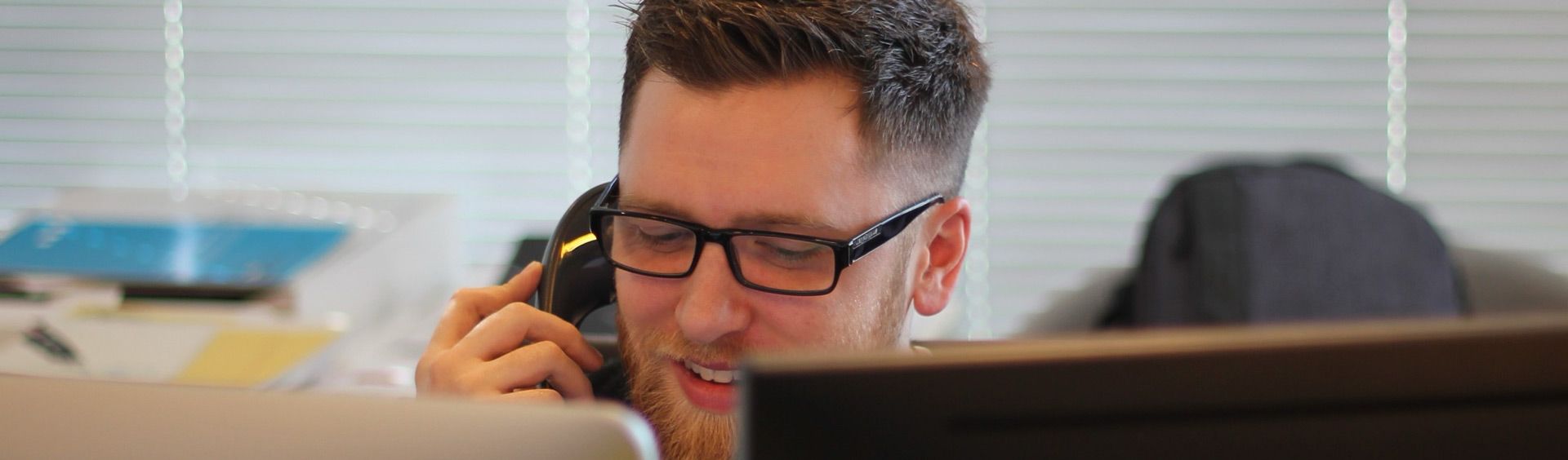person talking on the phone while looking at a computer screen